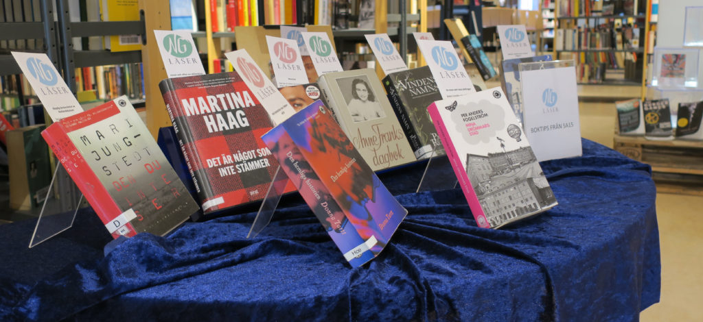 Utställning med NG läser-bokmärken i olika böcker, på ett bord med blå sammetsduk